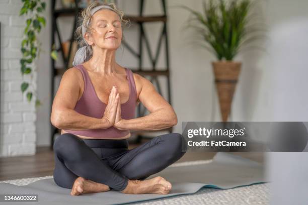 senior woman meditating at home - headband stock pictures, royalty-free photos & images
