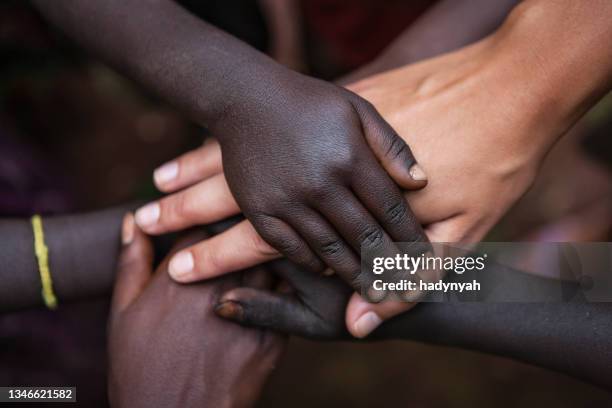 zusammengehörigkeit - multirassische menschenhände - black and white holding hands stock-fotos und bilder