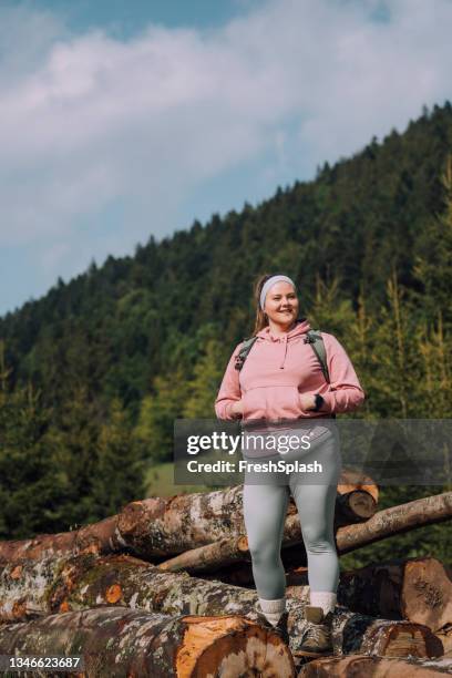 plus size woman in a pink sweatshirt hiking with a backpack on her back - obesity stock pictures, royalty-free photos & images