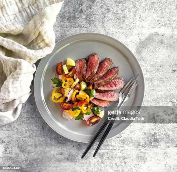 sliced steak with fresh salad on a plate on gray background - beef steak stock-fotos und bilder