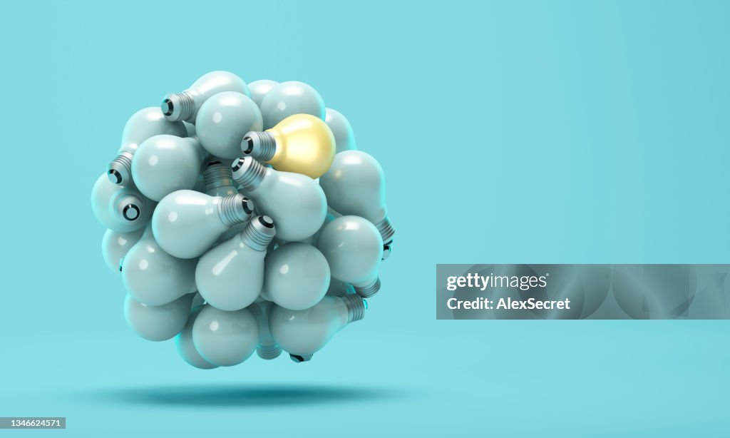 One glowing light bulb that stands out from unlit or dim lamps on a blue background