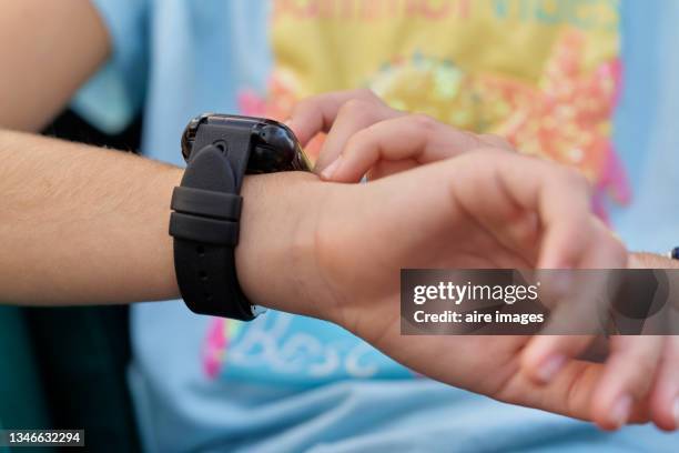 close-up of hands of a caucasian girl in casual clothing adjusting her smartwatch - smart watch on wrist stock pictures, royalty-free photos & images