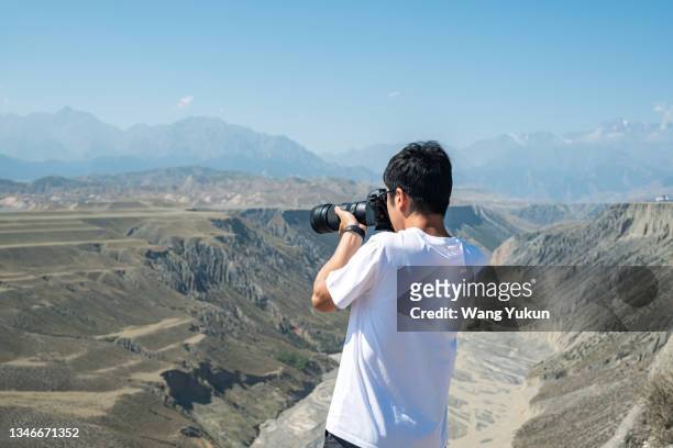 rear view of a male photographer using a camera to take pictures - 写真家 ストックフォトと画像