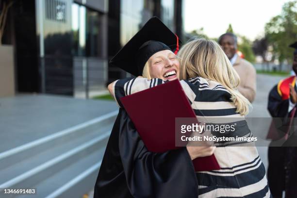 aufgeregte college-absolventin mit ihrer mutter nach der abschlussfeier - graduation hat stock-fotos und bilder