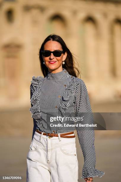 Alba Garavito Torre wears white pearl earrings, a gingham checkered black and white shirt with Long Sleeve Ruffles from Serendipia, Mom jeans in...