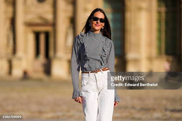 Alba Garavito Torre wears white pearl earrings, a gingham checkered black and white shirt with Long Sleeve Ruffles from Serendipia, Mom jeans in...