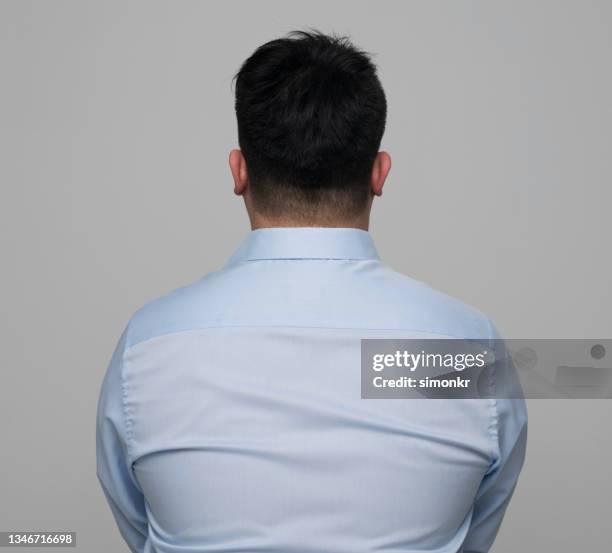 rear view of young man wearing light blue shirt - blue shirt stockfoto's en -beelden