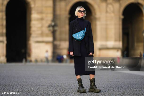 Emy Venturini wears sunglasses from Dita, a blue wool ribbed midi turtleneck dress from Cos, a black oversized blazer jacket from AntikBatik, a blue...