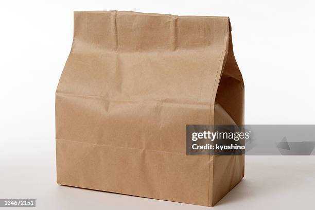 isolated shot of closed brown paper bag on white background - lunch bag white background stock pictures, royalty-free photos & images