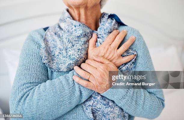 cropped shot of an unrecognizable senior woman suffering with chest pain while sitting in her room at the retirement home - chest pain stock pictures, royalty-free photos & images