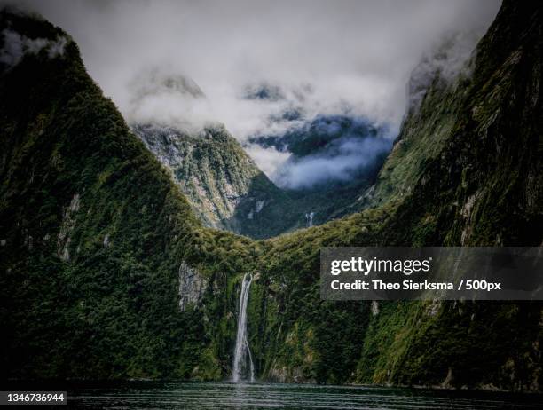 scenic view of waterfall against sky,milford sound,southland,new zealand - milford sound waterfall photos et images de collection