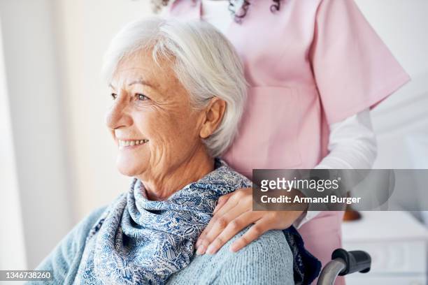 cropped shot of an attractive senior woman looking thoughtful while sitting with a nurse in her room at the retirement home - memories stock pictures, royalty-free photos & images