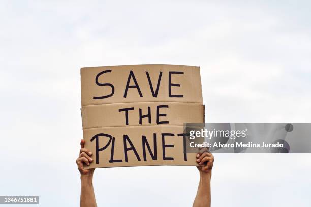 unrecognizable man's hands holding a protest banner with the message save the planet, with the sky in the background. - sign stock-fotos und bilder