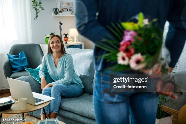 young woman smiling at her boyfriend who is about to surprise her with flowers - parcel laptop stock pictures, royalty-free photos & images