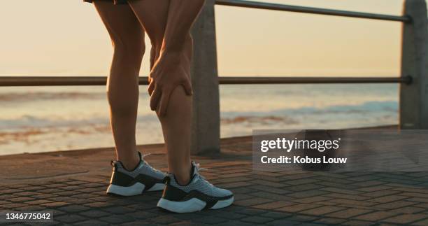 nahaufnahme eines nicht wiederzuerkennenden mannes, der sein bein vor schmerzen hält, während er entlang der promenade trainiert - pain & gain film stock-fotos und bilder