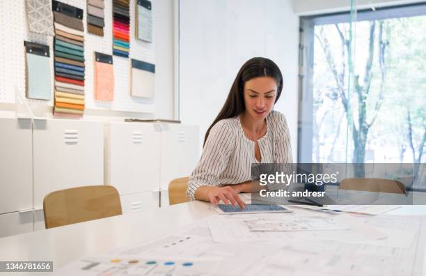 interior designer looking at pictures on her tablet at the office - interior design professional stock pictures, royalty-free photos & images