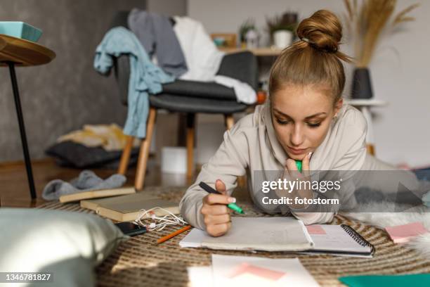teenager lying on the floor and highlighting notes while studying - teenager reading stock pictures, royalty-free photos & images