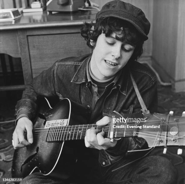 Scottish singer, songwriter and guitarist Donovan , UK, 13th February 1965. The words 'This Machine Kills' are written on his guitar.