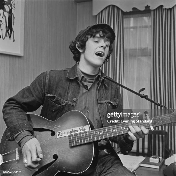 Scottish singer, songwriter and guitarist Donovan , UK, 13th February 1965. The words 'This Machine Kills' are written on his guitar.