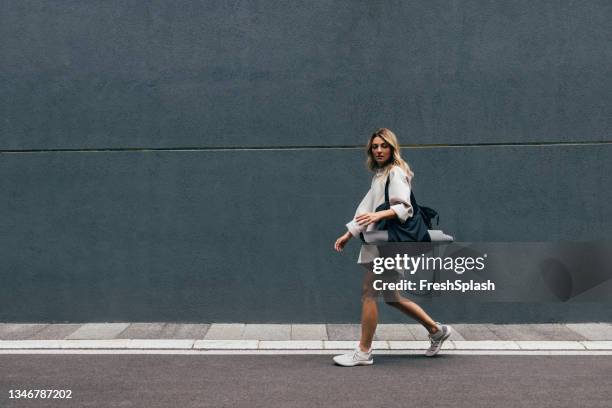 sportliche frau im weißen sweatshirt beim spazierengehen in der stadt - gray shoe stock-fotos und bilder