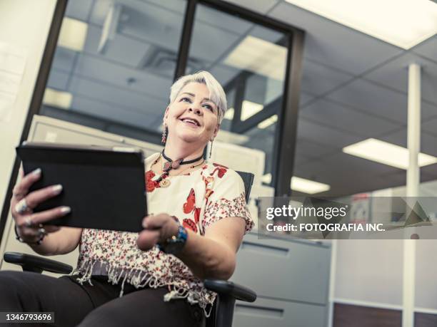 latin woman with disability using tablet in the office - deformed hand stock pictures, royalty-free photos & images