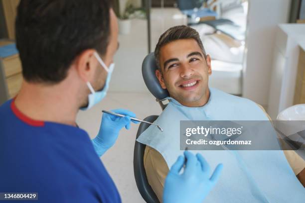 young man patient having dental treatment at dentist's office - dental visit stock pictures, royalty-free photos & images