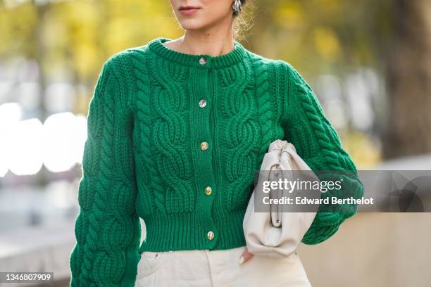 Katie Giorgadze wears a cable knit green wool cardigan from The Kooples, high rise off white denim jeans from Girlfriend, a pouch white leather...