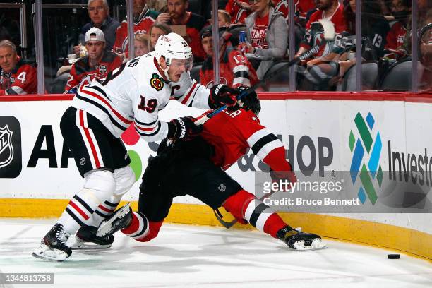 Jonas Siegenthaler of the New Jersey Devils is checked by Jonathan Toews of the Chicago Blackhawks during the first period at the Prudential Center...