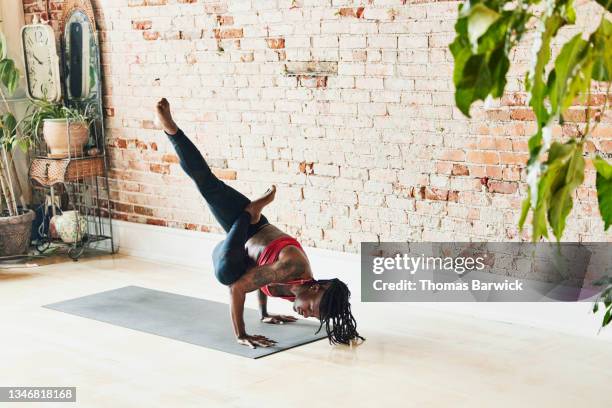 wide shot of woman in advanced handstand pose while practicing in yoga studio - yoga studio - fotografias e filmes do acervo