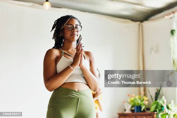 medium wide shot low angle view of woman relaxing after finishing yoga class in studio - woman fitness focus stock-fotos und bilder