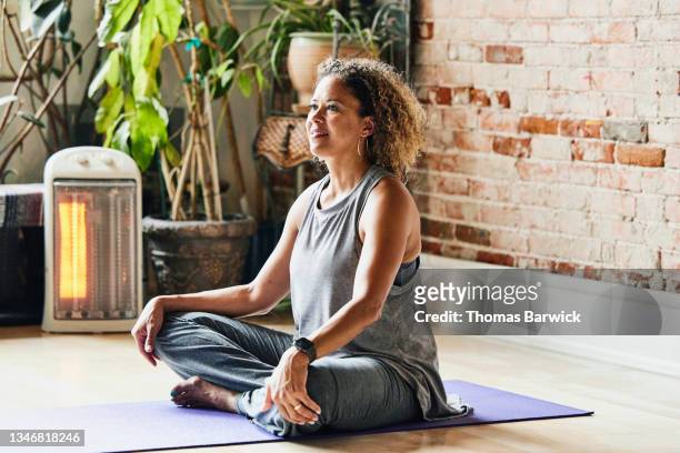 medium shot of smiling mature yoga instructor sitting in studio before class - donne bionde scalze foto e immagini stock