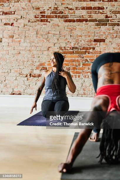 wide shot of smiling woman relaxing during class in yoga studio - african american woman barefoot stock pictures, royalty-free photos & images