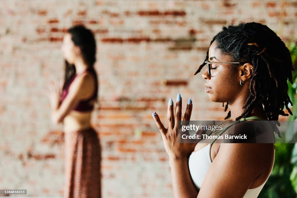 Medium wide shot of woman relaxing after practicing yoga during class in studio