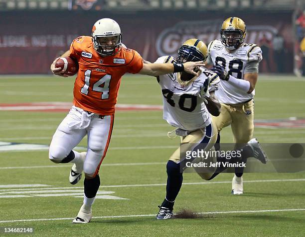 Travis Lulay of the BC Lions rushes upfield as he eludes the tackle of Odell Willis of the Winnipeg Blue Bombers during the CFL 99th Grey Cup...