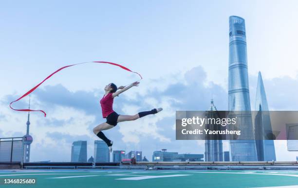 young female ballet dancer dancing with a red ribbon on a rooftop in shanghai,china - urban ballet stockfoto's en -beelden