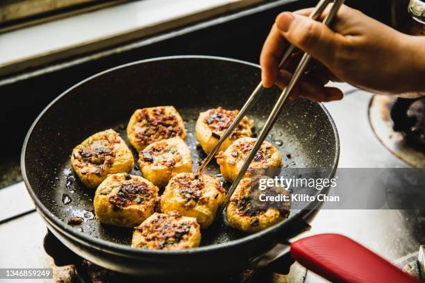 asian woman pan frying tofu with meat stuffing (酿豆腐)-traditional cantonese food - gebratener tofu stock-fotos und bilder