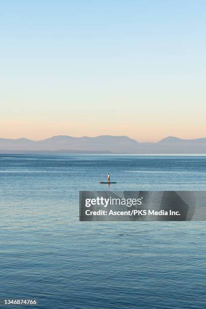 man paddle boards through open water at sunrise - simple living stock pictures, royalty-free photos & images