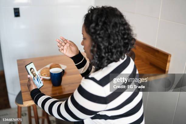 mid adult woman on a video call with a doctor at home - mentoring virtual stock pictures, royalty-free photos & images