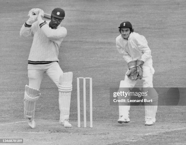 England wicketkeeper Alan Knott looks on from behind the stumps as batsman Clive Lloyd of the West Indies cricket team plays a drive off a delivery...