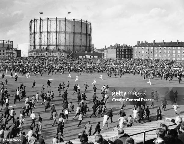 Players from the England cricket team run to the safety of the pavilion as crowds of spectators invade the pitch after the West Indies cricket team...