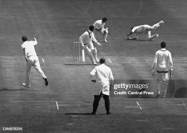 Batsman Garfield Sobers, captain of the West Indies cricket team and wicketkeeper Jim Parks look on as England slip fielder Colin Cowdrey dives in an...