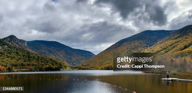 a lone tourist taking photos at echo lake in franconia notch state park in franconia, new hampshire during autumn - lake solitude (new hampshire) stock pictures, royalty-free photos & images