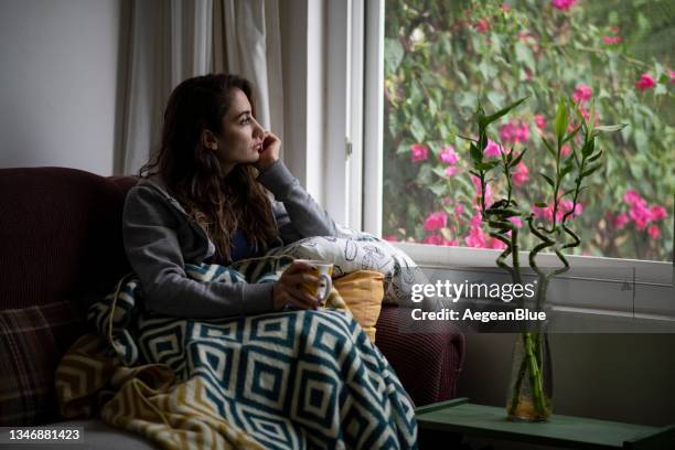 donna depressa seduta alla finestra - one young woman only foto e immagini stock
