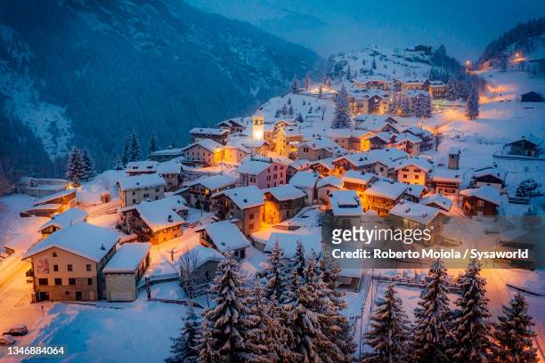 winter dusk over the small alpine village in the snow - isola stock-fotos und bilder