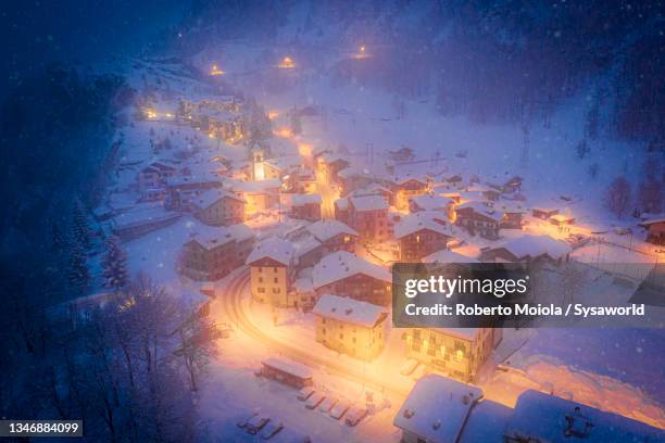 snowfall over the illuminated village at christmas - christmas city stockfoto's en -beelden