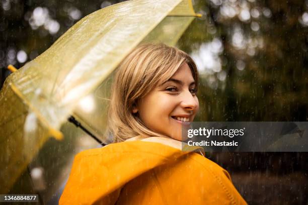 young woman with umbrella enjoying a rainy day - yellow umbrella stock pictures, royalty-free photos & images