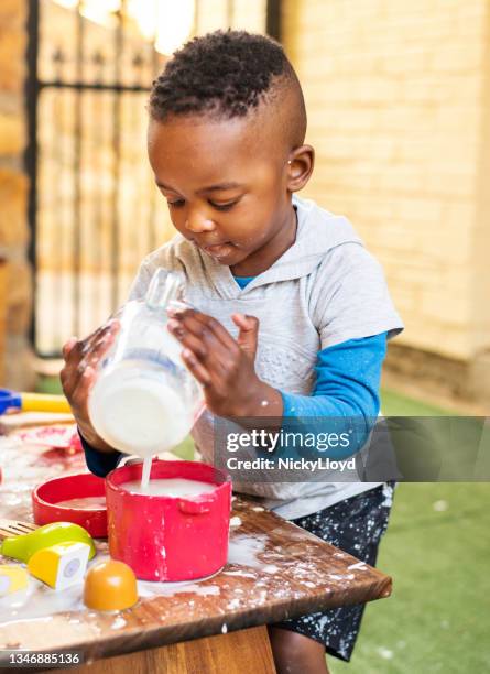 smiling little boy making a mess while playing at a table outside - toddlers playing outdoor stock pictures, royalty-free photos & images