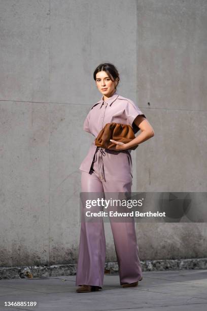 Katie Giorgadze wears faux leather wide leg lavender pants from J’amemme, a faux leather lavender / pale pastel purple shirt from J’amemme, a pouch...