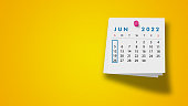 2022 June Calendar on Note Pad Against Yellow Background