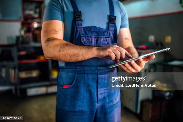 mechaniker bei der arbeit an berichten in einer werkstatt - auto zerlegt stock-fotos und bilder